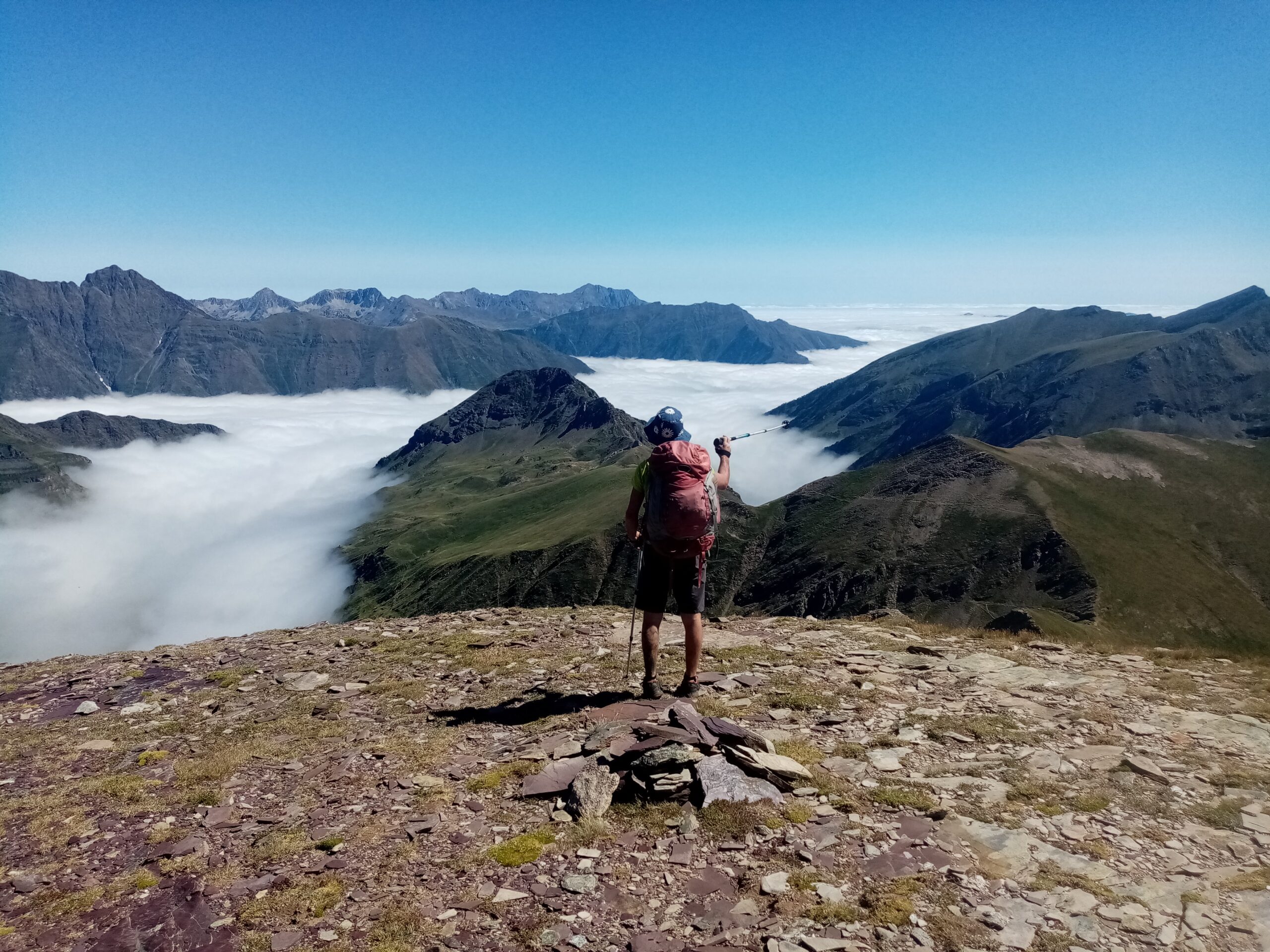 Un accompagnateur surplombe une mer de nuages où émergent des montagnes.